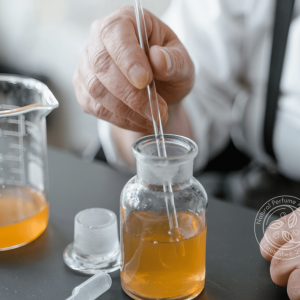 Perfumers hands stirring the added essences to a bottle