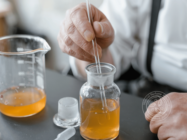 Perfumers hands stirring the added essences to a bottle