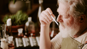 Experienced perfumer evaluating a fragrance sample on a scent strip in a natural perfumery setting.