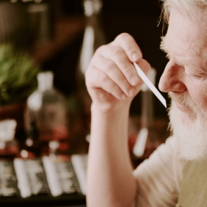 Experienced perfumer evaluating a fragrance sample on a scent strip in a natural perfumery setting.