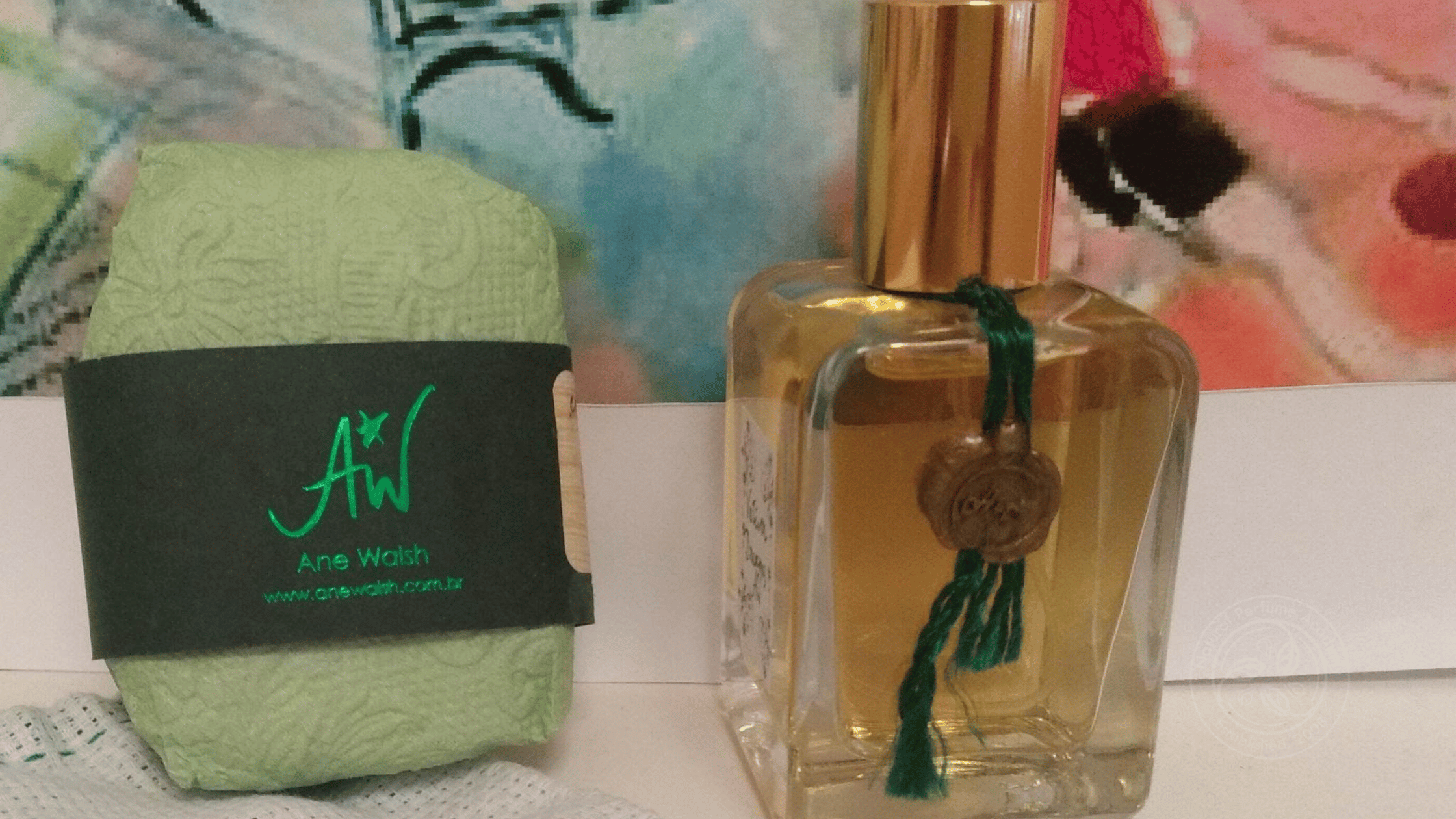 A green handmade soap bar by Ane Walsh wrapped in textured paper, paired with a natural perfume bottle adorned with a tassel and wax seal.